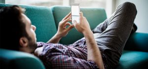 A person is laying on the couch looking at their phone.